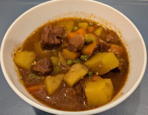 Home Hearty Soup, filled with Beef chunks, carrots, potatoes, peas, and onions, in a savory sauce.