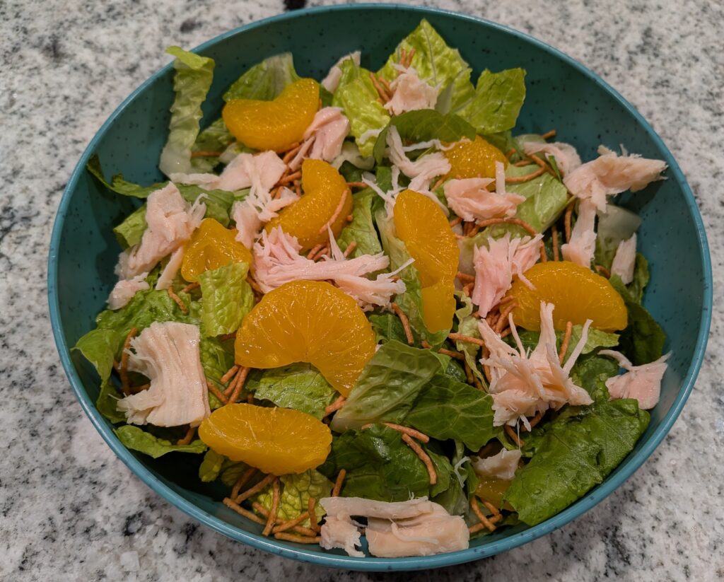Freshly chopped Romaine Lettuce, topped with Mandarin Oranges, Costco Chicken, and Asian-style Crunchy Noodles.