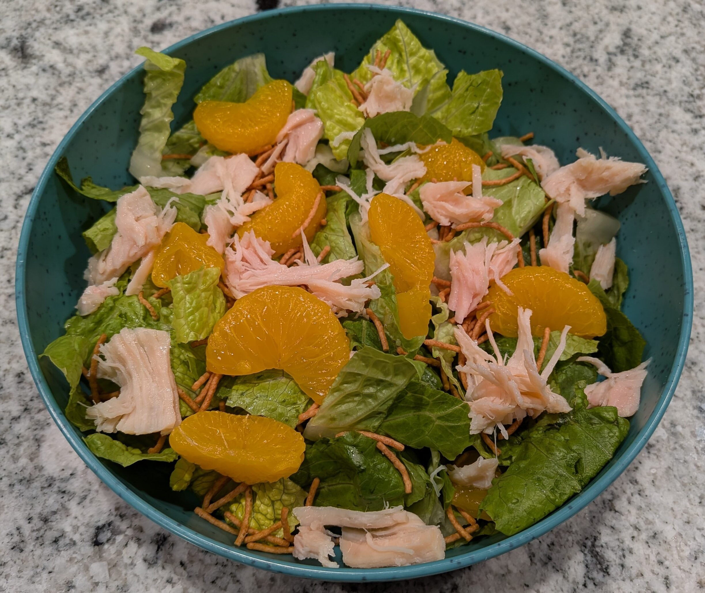Freshly chopped Romaine Lettuce, topped with Mandarin Oranges, Costco Chicken, and Asian-style Crunchy Noodles.