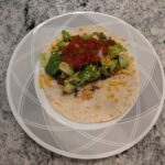 Flavored black beans wrapped in a warm freshly cooked tortilla topped with various toppings.