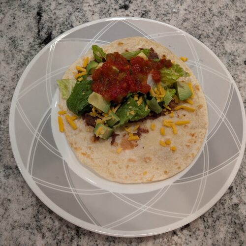 Flavored black beans wrapped in a warm freshly cooked tortilla topped with various toppings.