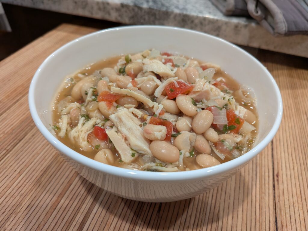Chicken surrounded by white beans, onions, and garlic in a savory broth.