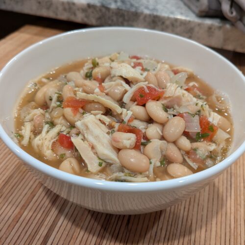 White Chicken Chili Chicken surrounded by white beans, onions, and garlic in a savory broth.
