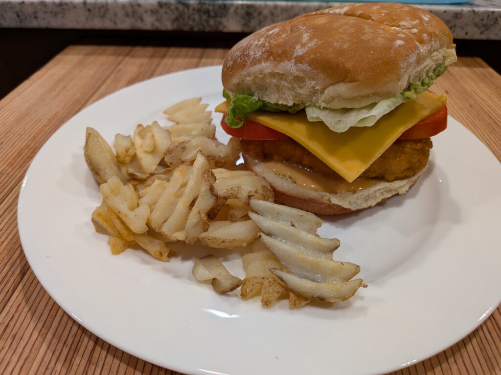 Homemade Chick-Fil-A. A lightly breaded chicken fillet in a bun topped with lettuce, cheese, and tomato.
