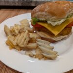 Homemade Chick-Fil-A. A lightly breaded chicken fillet in a bun topped with lettuce, cheese, and tomato.